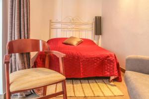 a bedroom with a bed with a red blanket and a chair at Elvas GuestHouse in Elvas