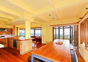 a large kitchen with a table and a fireplace at Cloudy Bay Villa in South Bruny