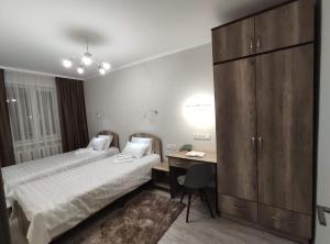 a hotel room with two beds and a desk at Lux Apartment Karakol Center in Karakol