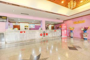 a restaurant with pink walls and vases of flowers at OYO 565 Trang Hotel in Trang