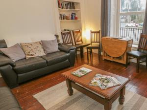 a living room with a leather couch and a table at 79 Laurel Bank in Gatehouse of Fleet