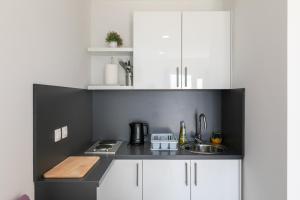 uma pequena cozinha com armários brancos e um lavatório em Apartments Karol & Mara em Mlini