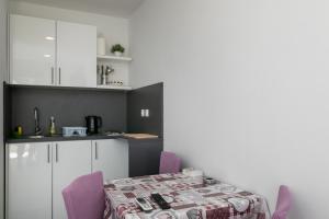 a kitchen with a table and purple chairs at Apartments Karol & Mara in Mlini