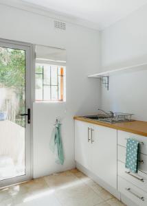 uma cozinha com armários brancos e um lavatório em Eden View Cottage, Sheffield Beach em Sheffield Beach