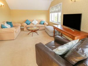 a living room with a television and a couch and a piano at Bryn y Don in Benllech