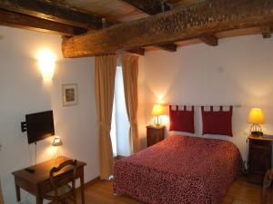 a bedroom with a red bed and a television at Hôtel du Donjon in Aulnay