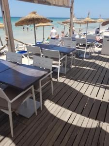 a deck with tables and umbrellas on the beach at Royal Thalassa Monastir in Monastir