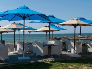 a group of tables and chairs with umbrellas on the beach at Royal Thalassa Monastir in Monastir