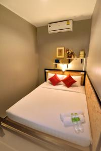 um quarto com uma cama branca e almofadas vermelhas em OK CHIC PHUKET HOSTEL em Phuket