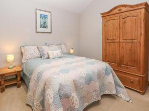 um quarto com uma cama e um armário de madeira em Maltkiln Cottage At Crook Hall Farm em Mawdesley