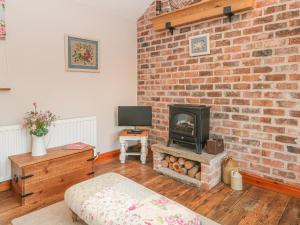 a living room with a brick wall and a fireplace at Maltkiln Cottage At Crook Hall Farm in Mawdesley