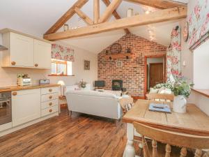 a kitchen and living room with a brick wall at Maltkiln Cottage At Crook Hall Farm in Mawdesley