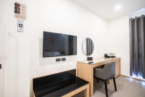 een kamer met een bureau en een televisie aan de muur bij Cubic Bangna in Bangkok