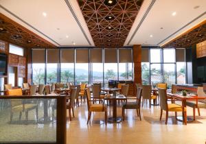 une salle à manger avec tables, chaises et fenêtres dans l'établissement Regenta Resort Belagavi, à Belgaum
