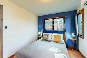 a bedroom with blue walls and a bed with pillows at Inn The Trees Cabañas in Placencia