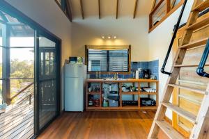 a kitchen with a refrigerator and a staircase at Inn The Trees Cabañas in Placencia Village