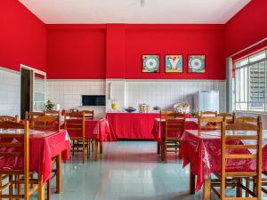 - une salle à manger avec des murs rouges, des tables et des chaises en bois dans l'établissement Palace Hotel Itapira, à Itapira