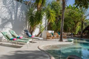 a group of chairs and a swimming pool with palm trees at Out of Africa Town Lodge in Otjiwarongo
