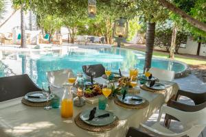 a table with food and drinks next to a swimming pool at Out of Africa Town Lodge in Otjiwarongo