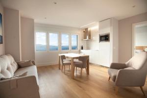 a living room with a table and chairs and a kitchen at Apartamentos Reina Victoria in Santander