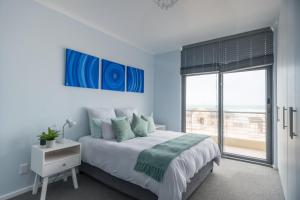 Un dormitorio con una cama grande y una ventana en At the Beach - Muizenberg, en Ciudad del Cabo