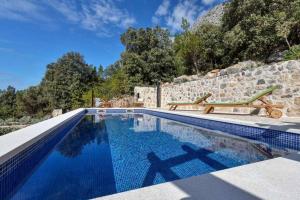 uma piscina com um banco ao lado de uma parede de pedra em Holiday home Marijana em Zaostrog