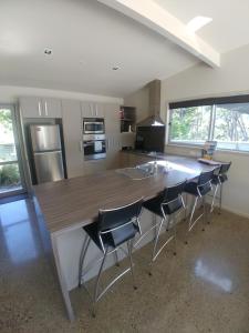 a kitchen with a large wooden counter with chairs around it at Ryder Ridge Holiday Home in Motueka