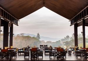 um restaurante com mesas e cadeiras e uma grande janela em Symphony Samudra Beachside Jungle Resort And Spa em Port Blair