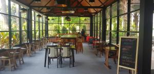 a restaurant with tables and chairs and windows at ร่มปาล์มรีสอร์ท สระบุรี Rompalm Saraburi in Sara Buri