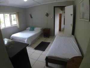 Habitación con 2 camas y espejo. en Ikaya Accommodation Psj en Port St Johns