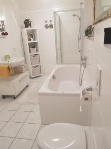 La salle de bains blanche est pourvue d'une baignoire et de toilettes. dans l'établissement Tillyhome, à Nuremberg