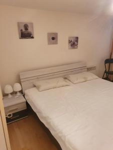 ein Schlafzimmer mit einem weißen Bett und zwei Bildern an der Wand in der Unterkunft Chalet-Etage mitten im Dorf von Leukerbad in Leukerbad