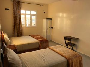 um quarto de hotel com duas camas e uma janela em Hôtel Afoulki Tiznit em Tiznit