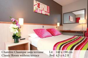 ジュアン・レ・パンにあるThe Originals Boutique, Hôtel Les Strélitziasのピンクの枕が付いたベッドが備わるホテルルームです。