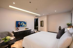 ein Schlafzimmer mit einem weißen Bett und einem Sofa in der Unterkunft Sen Grand Hotel & Spa managed by Sen Group in Hanoi