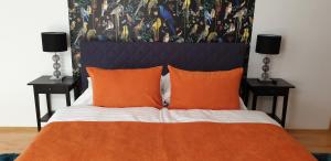 - une chambre avec un lit doté d'oreillers orange et de 2 lampes dans l'établissement Grand Paradise Apartman, à Miskolc
