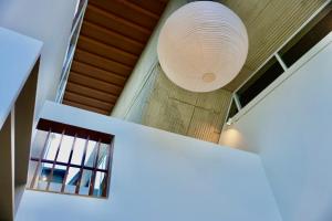 une grande lampe blanche suspendue au plafond d'une pièce dans l'établissement AandA Jonathan Hasegawa, à Okayama