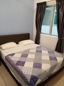 a bed with a quilt on it in a room with a window at Cameron's Square Apartment in Cameron Highlands