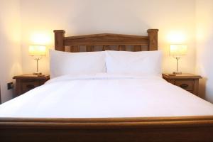 uma cama branca com duas lâmpadas em duas mesas em The Black Dog Inn em Dalton in Furness