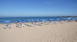 un grupo de sillas y sombrillas en una playa en TH Cinisi - Florio Park Hotel en Cinisi