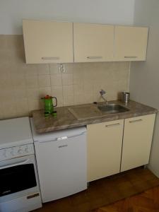 a small kitchen with white cabinets and a sink at Apartments Maslina in Sveti Stefan