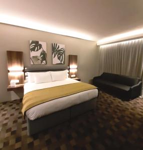 um quarto de hotel com uma cama grande e uma cadeira em Copperwood Hotel and Conferencing em Brits