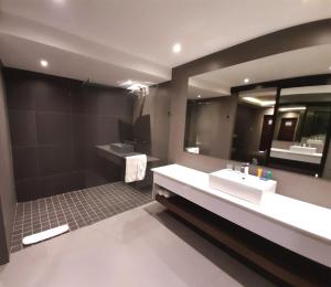 uma casa de banho com 2 lavatórios e um espelho grande em Copperwood Hotel and Conferencing em Brits