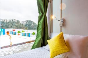 a bed with a yellow pillow in a room with a window at Zostel Mukteshwar in Mukteswar