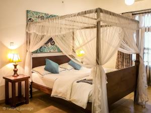 a bedroom with a canopy bed with white drapes at Gangula Villa in Kandy