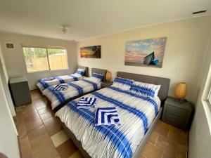a bedroom with two beds with blue and white sheets at Central Views in Jurien Bay