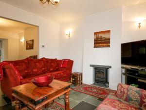 een woonkamer met een rode bank en een open haard bij Fountain Cottage in Keswick