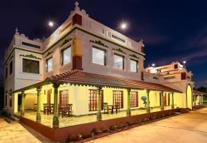 a yellow building with tables and chairs on a street at Marutham Village Resort in Mahabalipuram