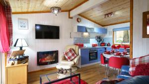 a living room with a kitchen and a table with a fireplace at Bluebell Lodge set in a Beautiful 24 acre Woodland Holiday Park in Newcastle Emlyn