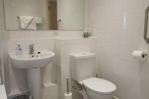 a white bathroom with a toilet and a sink at Toothbrush Apartments - Ipswich Waterfront South - Avalon Court in Ipswich +11 photos